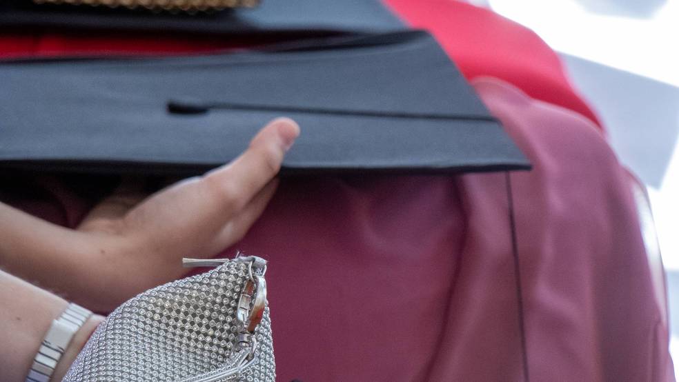 Personen halten Abschlusskappen und eine Handtasche.